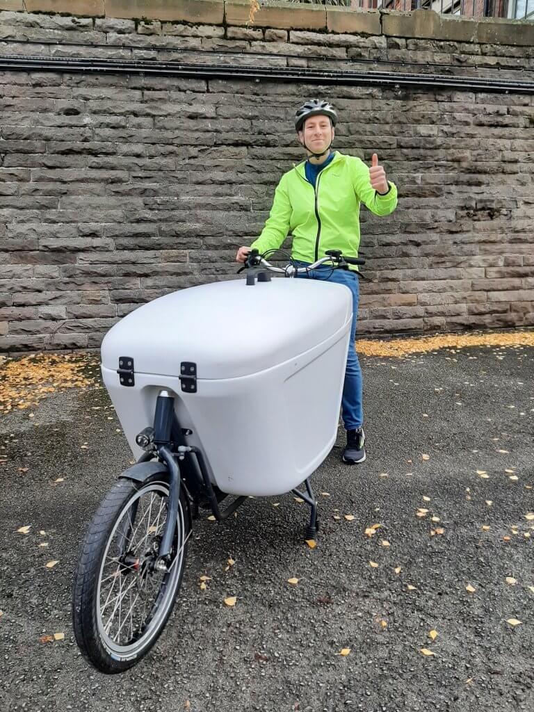 Our colleague Ross sat on an e-cargo bike full of cycle maps giving the camera a thumbs up