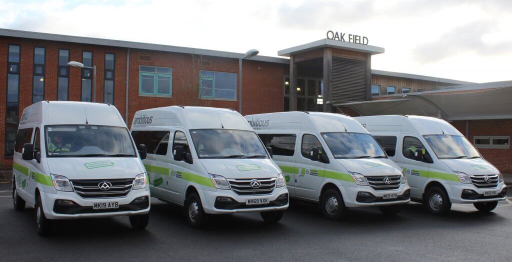 Four electric minibuses in front of Oakfield school