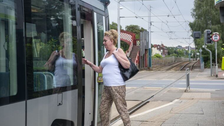 A woman stepping onto a tram