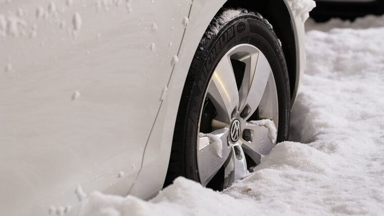 Car wheel buried in snow