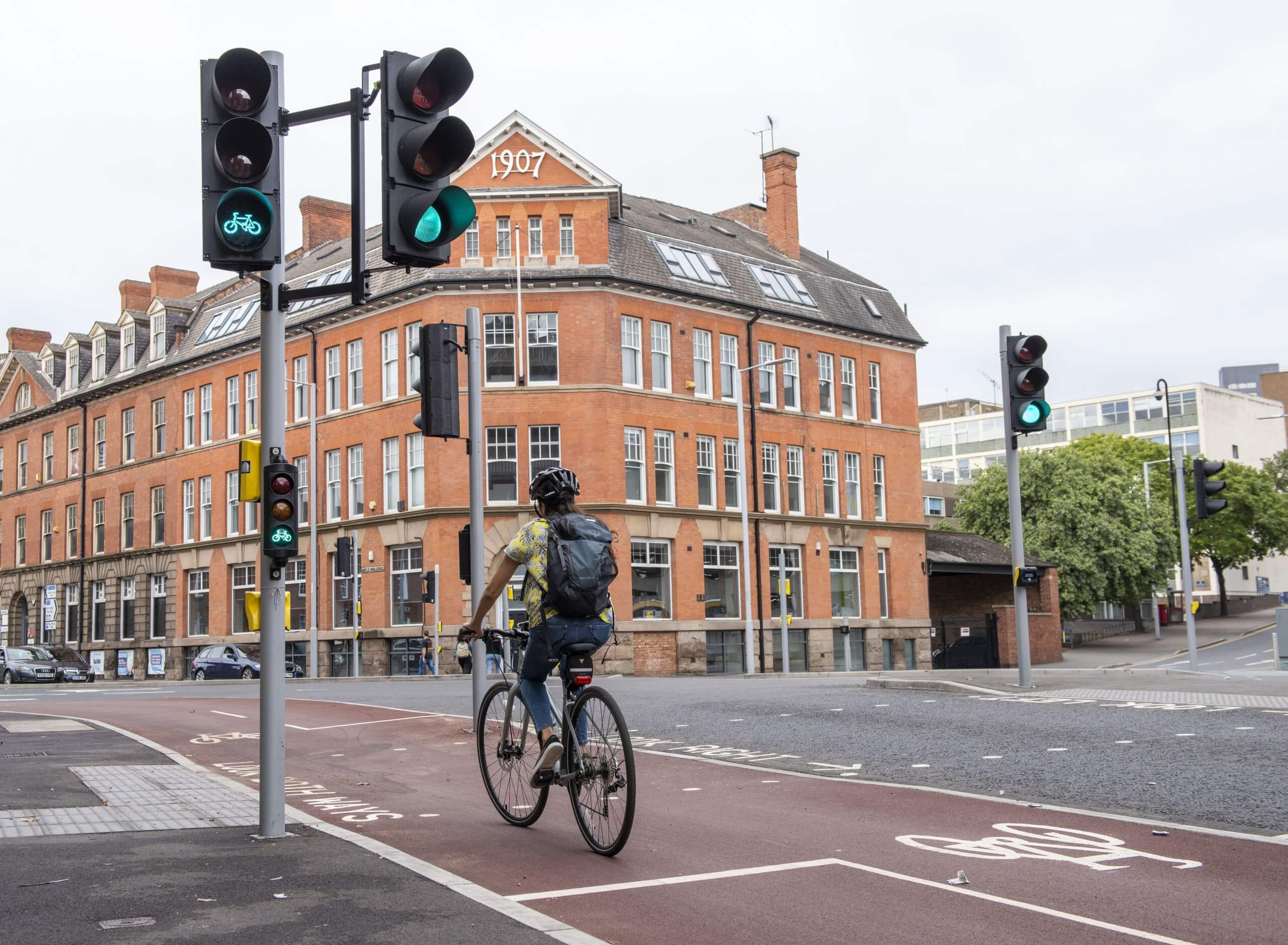 A lady cycling through a green cycle signal on the new cycle lane on Canal Street