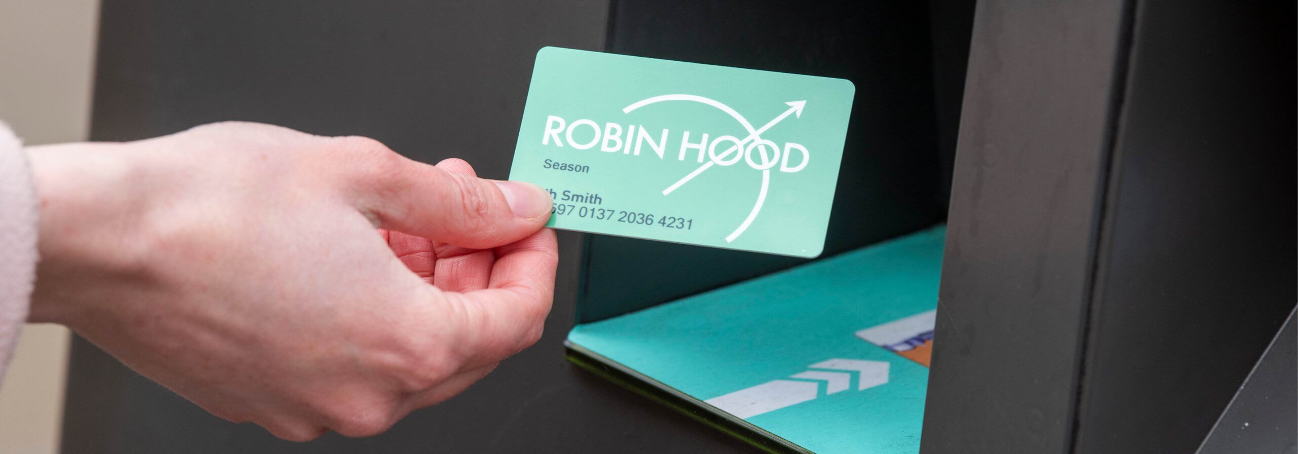 Hands holding a robin hood card at a top up machine