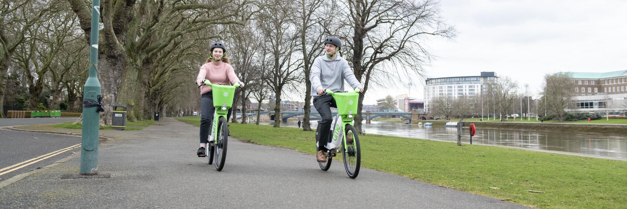 A man and woman riding E-bikes along the embankment in winter